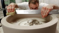 Ein Mitarbeiter der Porzellanfabrik Hermsdorf prüft und korrigiert die Oberfläche eines Werkstücks aus Rohware, das für eine Porzellanmühle zum Mahlen von Hartstoffen bestimmt ist.