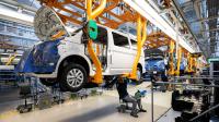 Ein Karosserie- und Fahrzeugbaumechaniker arbeitet unter einem Transporter im Werk von Volkswagen Nutzfahrzeuge.
