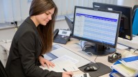 Eine Kauffrau für Kurier-, Express- und Postdienstleistungen berechnet die Kosten für Liefertouren beim Paketdienstleister Hermes.