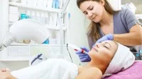Eine Kosmetikerin behandelt das Gesicht ihrer Kundin mit einem Mesotherapiegerät.