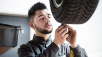 Ein Mechaniker für Reifen- und Vulkanisationstechnik überprüft das Profil eines Autoreifens.
