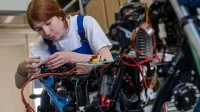 Eine Mechatronikerin repariert ein Motorrad.