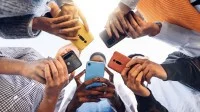 Junge Menschen stehen mit ihren Smartphones im Kreis