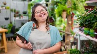 Frau mit Down-Syndrom arbeitet in einem Blumenladen mit Tablet