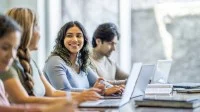 Drei Frauen und ein Mann sitzen vor ihren Laptops und lernen.