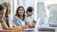 Drei Frauen und ein Mann sitzen vor ihren Laptops und lernen.