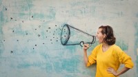 Eine Frau schreit durch ein Megafon, welches als Graffiti an die Wand gemalt ist.