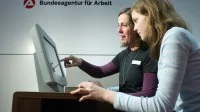 Eine Fachangestellte für Arbeitsmarktdienstleistungen berät eine Jugendliche an einem Stand der Bundesagentur für Arbeit über Ausbildungsberufe.