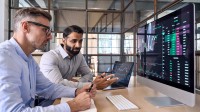 Zwei Kaufmänner für Digitalisierungsmanagement diskutieren Statistiken zu den Finanzen des Unternehmens.