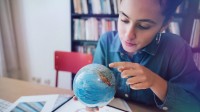 Junge Frau sucht auf dem Globus nach einem Land