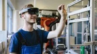 Ein junger Auszubildender wird in einer Werkstatt mit einer VR-Brille geschult.