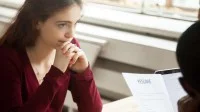Eine junge Frau in einem Bewerbungsgespräch wirkt besorgt und traurig.