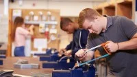 Auszubildende sägen in der Werkstatt.
