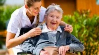 Altenpflegerin mit einer Seniorin im Rollstuhl