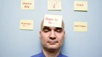 Mann hat geschlossene Augen und sechs gelbe Post-It um sich herum  