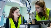 Auszubildende arbeiten an einem Roboterarm