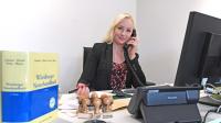 Eine Notarfachangestellte kümmert sich um die telefonische Korrespondenz mit einem Mandanten.
