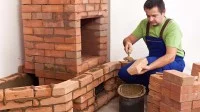 Ein Ofen- und Luftheizungsbauer mauert einen Backsteinofen.