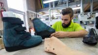 Ein Orthopädieschuhmacher prüft einen fertiggestellten orthopädischen Schuh.