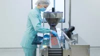 Eine Pharmakantin arbeitet in einem Pharmazieunternehmen an der Produktion von Tabletten.