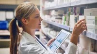 Eine Pharmazeutisch-kaufmännische Angestellte prüft den Medikamentenbestand in der Apotheke.