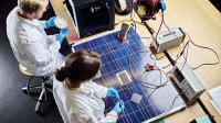 Zwei Physiklaboranten arbeiten an einem 3D-gedrucktem Turbinenrad und an einem Solarpanel.