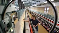 Eine Polster- und Dekorationsnäherin arbeitet an einer fast 30 Meter langen computergesteuerten Stickmaschine zur Fertigung von Gardinen der Marke Plauener Spitze.