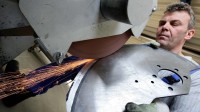 Ein Präzisionswerkzeugmechaniker der Firma Astor Schneidwerkzeuge GmbH schleift ein Industriemesser aus rostbeständigem Spezialstahl.