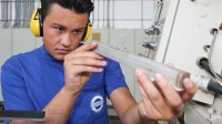 Eine Produktionsfachkraft Chemie der Firma Hermes Schleifmittel kontrolliert ein Werkstück aus Metall.