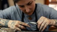 Eine Silberschmiedin fertigt in ihrer Werkstatt eine Kette an.