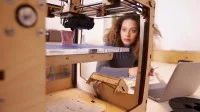 Eine Technische Produktdesignerin überwacht den 3-D-Druck eines Prototyps.