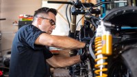Ein Zweiradmechatroniker repariert in der Werkstatt ein Motorrad.