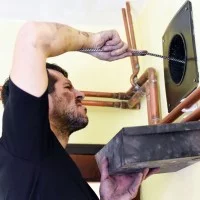 Ein Schornsteinfeger reinigt ein Rohr.