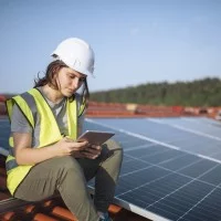 Umwelttechnikerin prüft Solaranlagen auf einem Dach