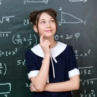 Eine nachdenkliche Schülerin steht vor einer schwarzen Tafel auf der mathematische Formeln angeschrieben sind.