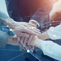 Eine Fotografie von drei Personen, die in der Mitte des Bildes die Hände übereinander legen. Darüber ist ein virtuelles Netz gespannt.