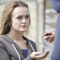 Ein Jugendlicher übergibt einer Jugendlichen ein Plastiktütchen mit vier Pillen.  