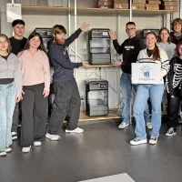 Lehrkräfte und Schülerinnen und Schüler der Louis-Lepox-Schule vor einem 3-D-Drucker