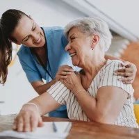 Pflegefachkraft umarmt ältere Patientin