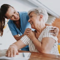 Pflegefachkraft umarmt ältere Patientin