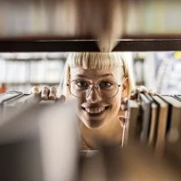 Junge Frau am Bücherregal in einer Bibliothek