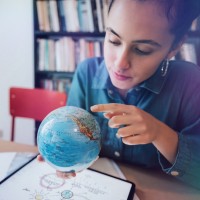 Junge Frau sucht auf dem Globus nach einem Land