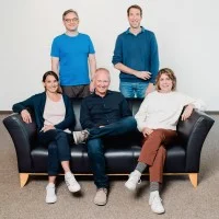 Das Team von HubbS, 3 Personen sitzen auf einem Sofa, 2 Personen stehen dahinter.
