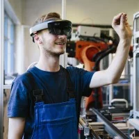 Ein junger Auszubildender wird in einer Werkstatt mit einer VR-Brille geschult.