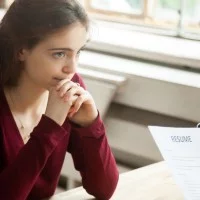 Eine junge Frau in einem Bewerbungsgespräch wirkt besorgt und traurig.