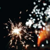 Eine gezündete Wunderkerze auf dunklem Hintergrund mit Reflektion.