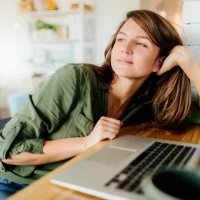 Junge Frau denkt am Laptop nach