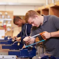 Auszubildende sägen in der Werkstatt.