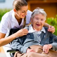 Altenpflegerin mit einer Seniorin im Rollstuhl