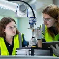 Auszubildende arbeiten an einem Roboterarm
